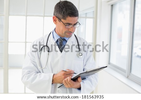 Serious male doctor writing reports in the hospital