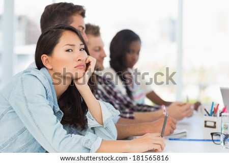 Bored woman looking at camera during a meeting in creative office