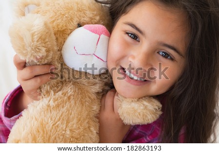 Close-up portrait of a young smiling girl with stuffed toy