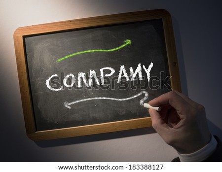 Hand writing the word company on black chalkboard