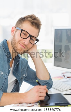 Handsome designer working with graphics tablet smiling at camera in creative office