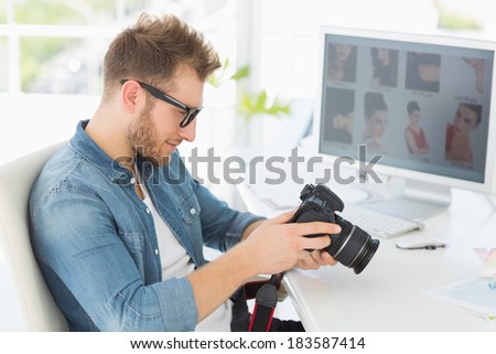 Handsome photographer looking at his camera in creative office