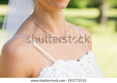 Midsection closeup of bride wearing necklace in garden