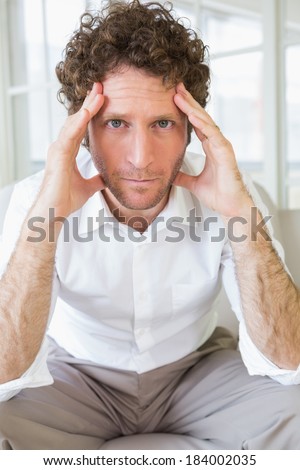 Portrait of a worried well dressed man sitting with head in hands on sofa in the house