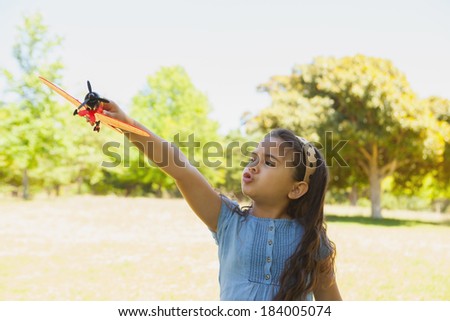 Portrait of a young girl playing with a toy plane at the park