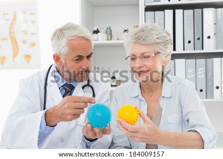 Male doctor showing stress buster balls to senior patient at the medical office