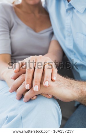 Couple showing wedding ring on womans finger on the couch at home in the living room