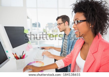 Side view of casual young couple working on computers in a bright office