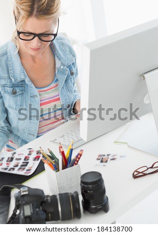 Blonde photographer looking over contact sheet at her desk in creative office