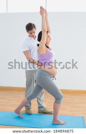 Pregnant woman doing yoga with a personal trainer in a fitness studio