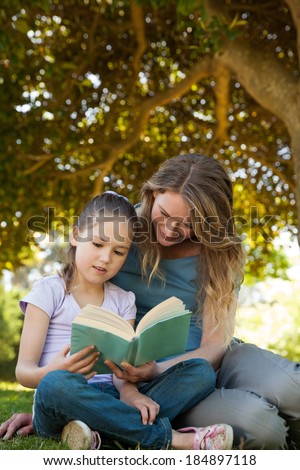Full length of a mother and daughter reading a book at the park