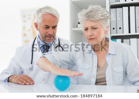 Male doctor with senior patient using stress buster ball at the medical office