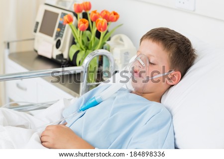 Sick little boy wearing oxygen mask in hospital ward