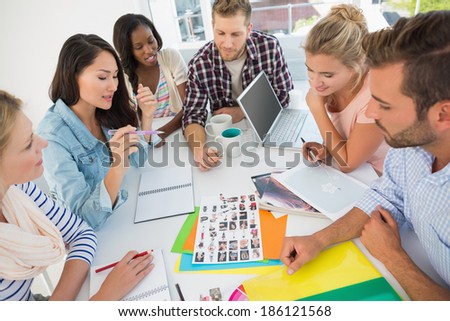 Young design team going over contact sheets at a meeting in creative office