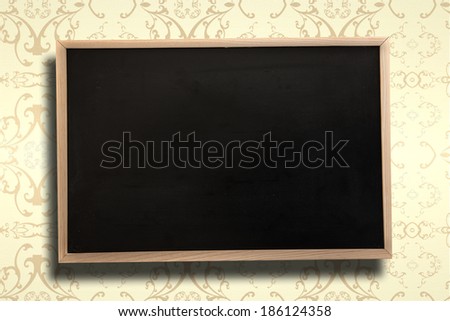 Chalkboard with wooden frame against elegant patterned wallpaper in cream tones
