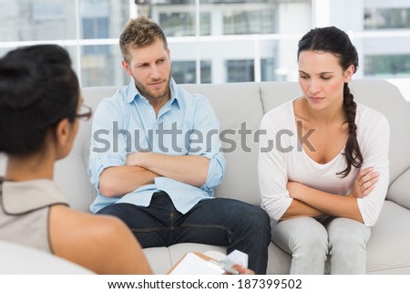 Unhappy couple with arms crossed at therapy session in therapists office