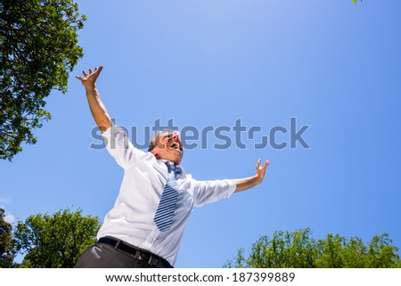 Low angle view of excited businessman screaming against blue sky