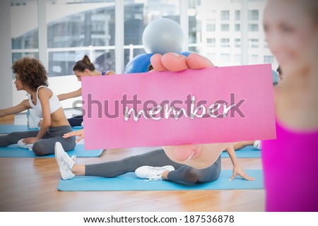Fit blonde holding card saying member against yoga class in gym