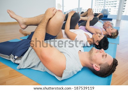 Side view of fitness class stretching legs in row at yoga class