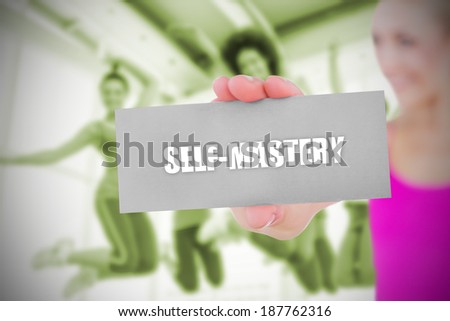 Fit blonde holding card saying self mastery against dance class in gym