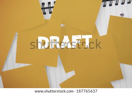 The word draft against yellow paper strewn over notepad