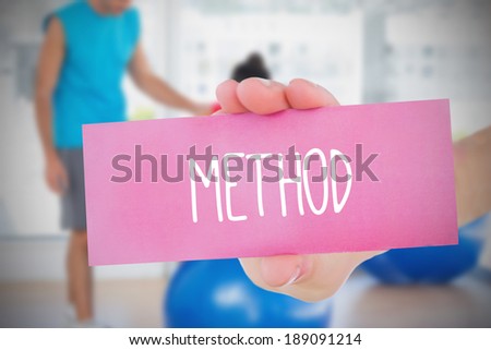 Woman holding pink card saying method against fitness class in gym