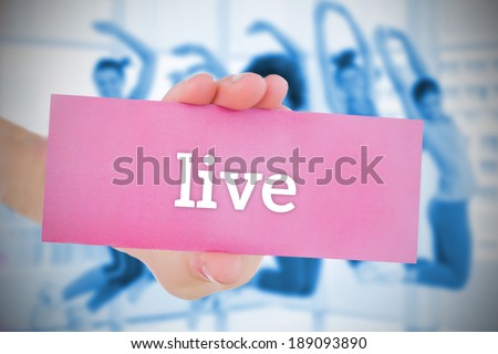 Woman holding pink card saying live against dance class in gym