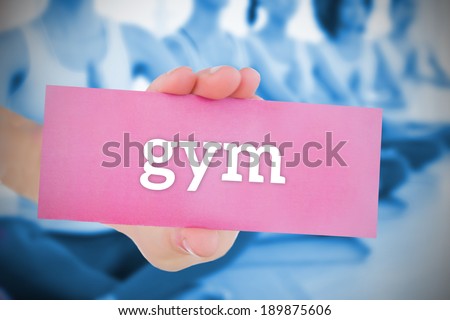 Woman holding pink card saying gym against yoga class in gym