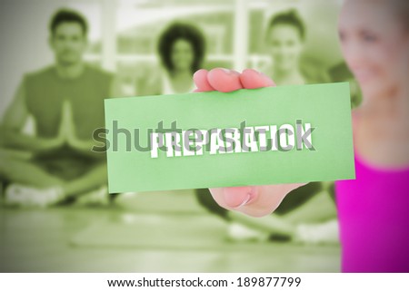 Fit blonde holding card saying preparation against yoga class in gym