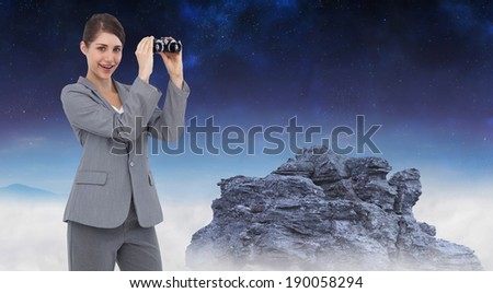 Businesswoman posing with binoculars against rocky landscape