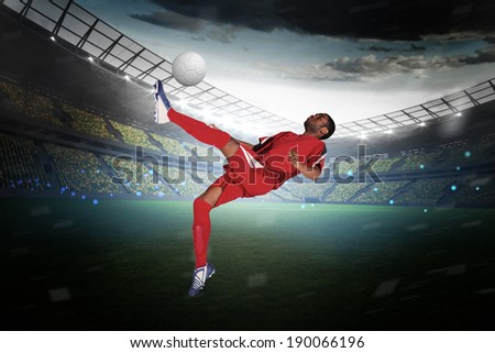 Football player in red kicking in a large football stadium with lights