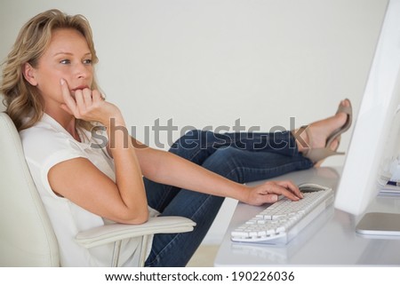 Casual businesswoman working with her feet up at desk in her office
