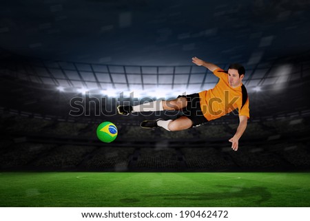 Football player in orange jumping against large football stadium with fans in yellow