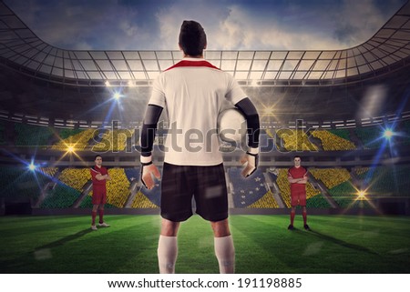 Composite image of goalie facing opposition against large football stadium with brasilian fans