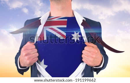 Businessman opening shirt to reveal australia flag against beautiful orange and blue sky