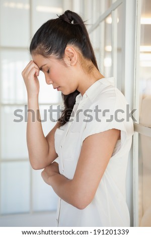 Casual upset businesswoman with head bowed in the office