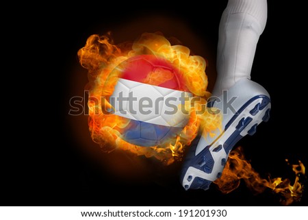 Football player kicking flaming netherlands ball against black