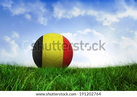 Football in germany colours on field of grass under blue sky