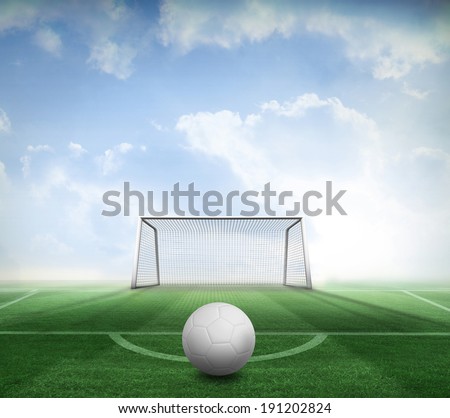 Digitally generated white leather football against football pitch and goal under blue sky