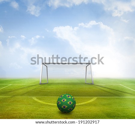 Football in brazilian colours against football pitch and goal under blue sky