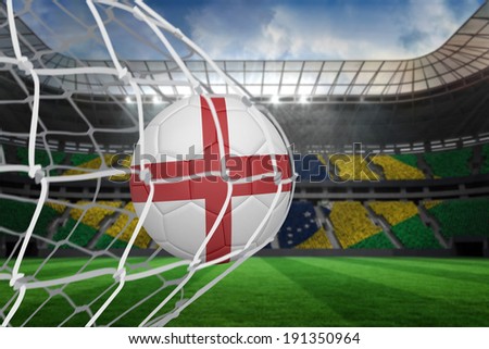 Football in england colours at back of net against large football stadium with brasilian fans