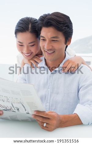 Couple reading a newspaper together outside on a balcony