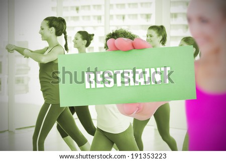 Fit blonde holding card saying restraint against fitness class in gym