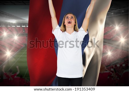 Cheering football fan in white holding russia flag against vast football stadium with fans in red