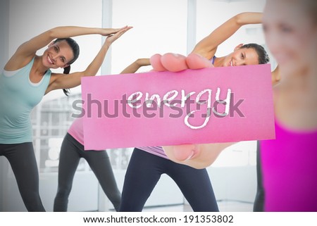 Fit blonde holding card saying energy against fitness class in gym