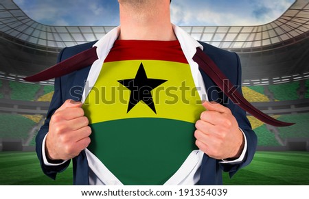 Businessman opening shirt to reveal ghana flag against large football stadium with brasilian fans