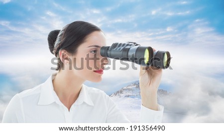 Business woman looking through binoculars against misty landscape
