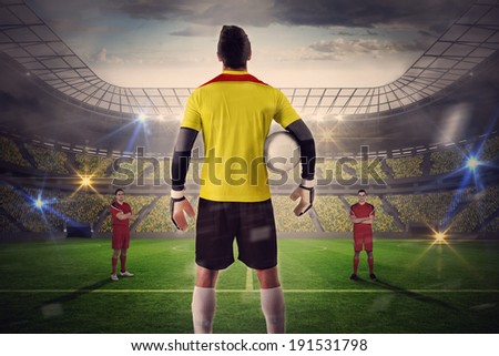 Composite image of goalie facing opposition against large football stadium with lights