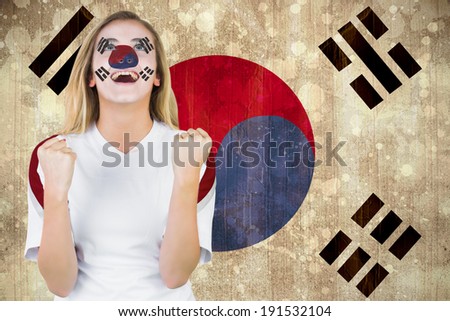 Excited south korea fan in face paint cheering against korea republic flag in grunge effect