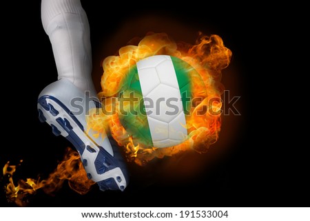 Football player kicking flaming nigeria ball against black